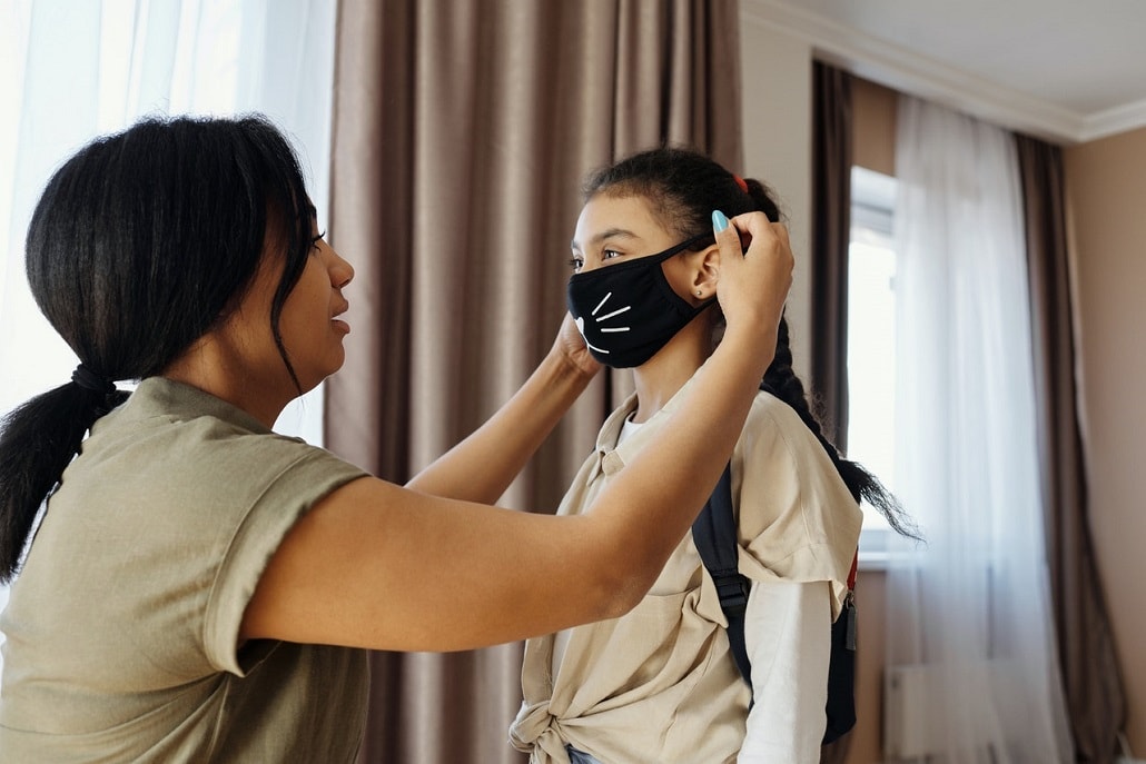 Matka ubiera dziecku maskę przeciw koronawirusowi