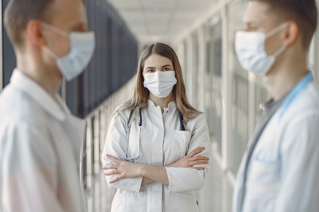 Lekarze w maseczkach w szpitalu na korytarzu w białych kitlach