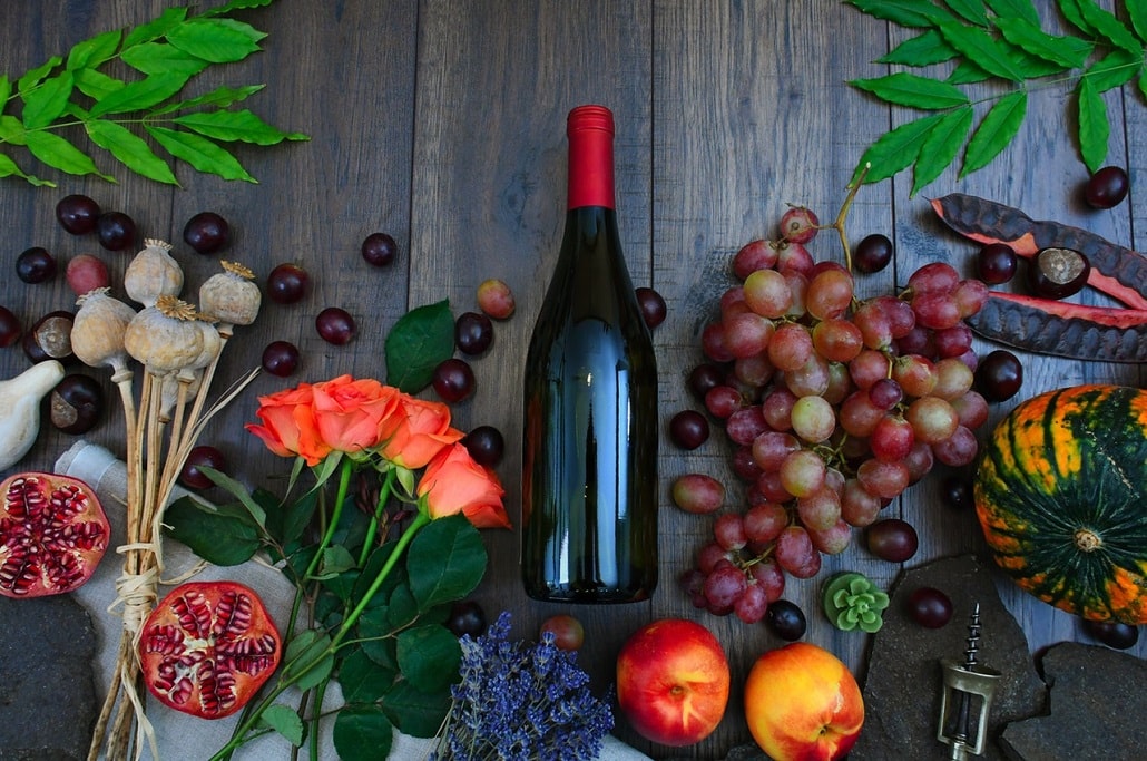 Butelka wina otoczona owocami, z których można je robić