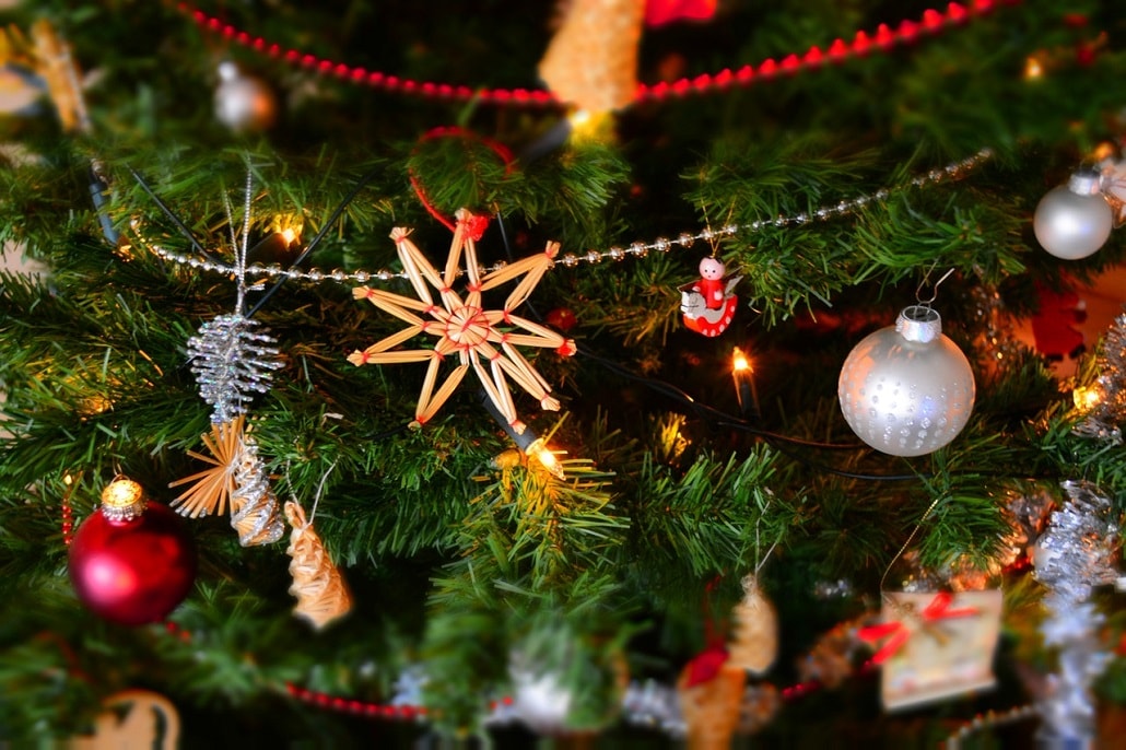 Choinka bożonarodzeniowa ozdobiona bombkami, łańcuchami i drewnianymi detalami