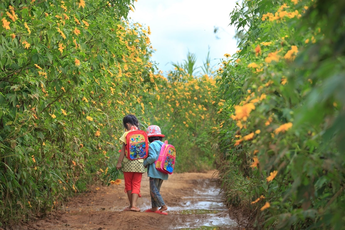 Dwie dziewczynki na spacerze, otoczone krzakami i kwiatami