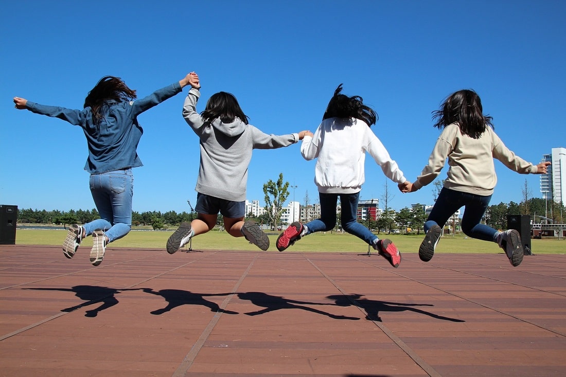 Cztery dziewczyny skaczą trzymając sie za ręce